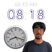 a man wearing glasses stands in front of a clock that says 08:18