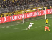 a soccer player kicks the ball in front of a turkish airlines sign