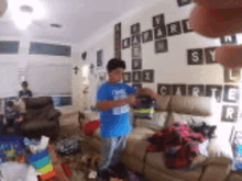 a young boy in a blue shirt is playing a video game in a living room