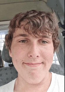 a young man with curly hair and freckles looks at the camera