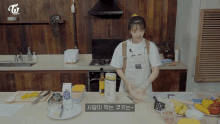 a woman in an apron is preparing food in a kitchen with a twice logo on the wall behind her