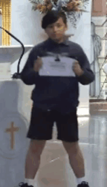 a young boy is standing in front of a podium holding a piece of paper in his hands .