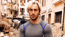 a man with white hair and a beard is standing in front of a pile of rubble in a city .