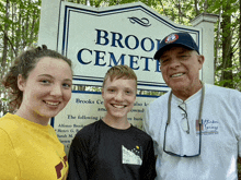 a man and two children pose in front of a sign for brooks cemetery