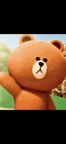 a brown teddy bear with a white face is waving his hand