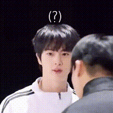 a young man with a question mark on his head talking to another man .