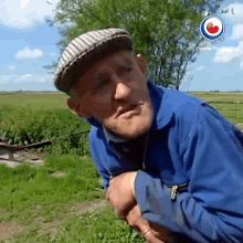 a man wearing a plaid hat and a blue jacket is standing in a field with omrop fryslân written on the bottom