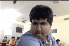 a man in a blue shirt making a funny face in a classroom