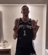 a man wearing a spurs jersey is giving a peace sign