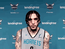 a man in a hornets jersey stands in front of a wall with hornets logos