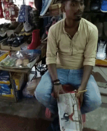 a man is sitting in front of a shoe store holding a box with a picture of a person on it