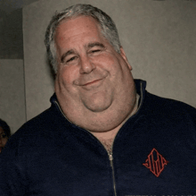a man with a large neck and a blue jacket with a monogram on it