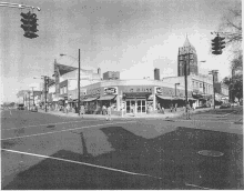 a black and white photo of a corner store with coca cola written on the front