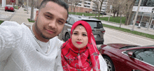 a man and a woman are posing for a selfie in front of a car