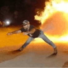 a man is standing in front of a fireball in the dark .