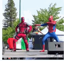 deadpool and spider-man are dancing on a stage in front of a dj .