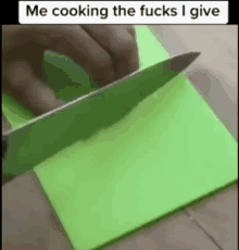 a person is cutting a piece of green paper with a knife