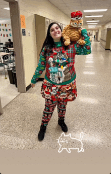 a woman in a christmas sweater holds a stuffed cat