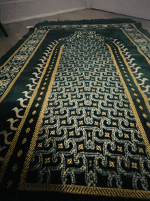 a green rug with a gold border has a pattern that looks like a puzzle