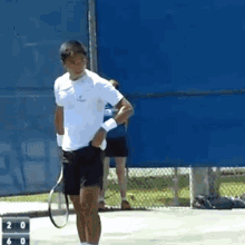 a man is holding a tennis racquet on a tennis court with a scoreboard behind him that says 20 and 60