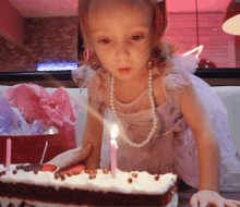 a little girl is blowing out candles on a cake