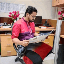 a man in a red shirt is reading a newspaper