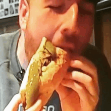 a man is eating a large sandwich with a pickle on it .