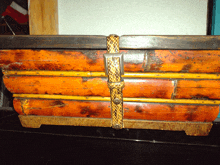 a very old wooden box with a snake buckle