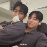 two men are sitting next to each other and one has a bandage on his nose
