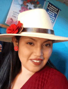 a woman wearing a white hat with a red flower on it smiles