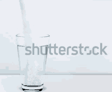 a glass of water is being poured with the word shutterstock in the background