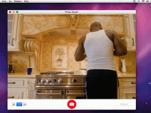 a man in a white tank top is standing in front of a stove with a photo booth app open