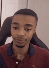 a man with a tattoo on his neck is wearing a maroon shirt