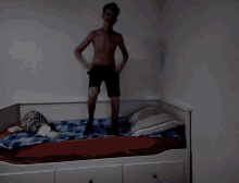 a shirtless man is standing on a bed pointing