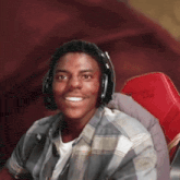a young man is wearing headphones and smiling while sitting in a red chair .