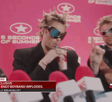 a man drinking from a straw in front of a 5 seconds of summer banner