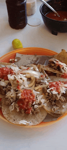 a close up of a plate of food with a bottle of sauce in the background