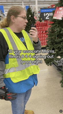 a woman in a yellow vest is talking on a walkie talkie in front of a christmas tree