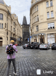 a man with a backpack is walking down a cobblestone street in front of a building that says lively on the bottom