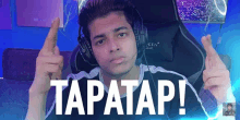 a young man wearing headphones is pointing up and says tapatap