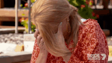 a woman covering her face with her hand while wearing a red dress with bride prejudice written on the bottom