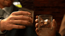 two men toast with glasses of whiskey and ice cubes
