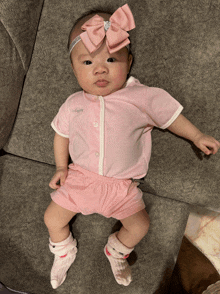 a baby wearing a pink shirt and shorts with a bow on her head