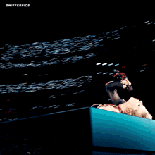 a woman singing into a microphone with swifterpics written on the bottom right