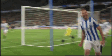 a man in a blue and white striped shirt is standing on a soccer field in front of a goal