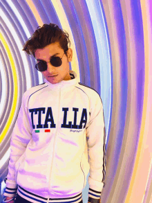 a man wearing sunglasses and a white jacket with the word italia on it