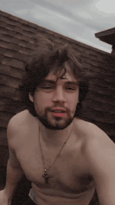 a shirtless man with a beard and a cross on his neck