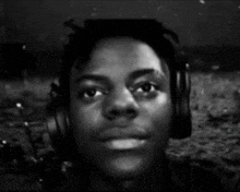 a young man wearing headphones looks at the camera