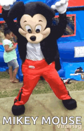 a mickey mouse mascot is dancing in front of a girl