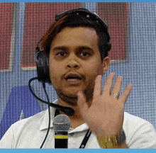 a man wearing headphones and a microphone waves his hand .